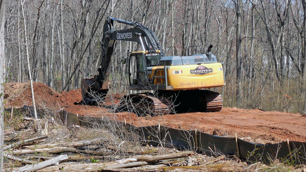 An excavator scoops dirt on the construction site of the Farmington Canal Heritage Trail, Plainville 1 project